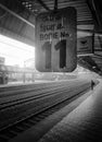 A lonely platform with a signpost and a passenger on the platform.