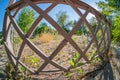 Image shows an off-center, tilted circular wooden frame with a lattice pattern and vegetation inside The background Royalty Free Stock Photo
