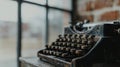A black vintage typewriter sits on a wooden table, with a brick wall and window in the background. Royalty Free Stock Photo