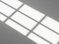 Sunlight casting a grid pattern through blinds on a plain surface Royalty Free Stock Photo