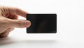 A hand holding a sleek black rectangular device against a plain background Royalty Free Stock Photo