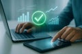 Person using laptop and tablet with glowing charts and checkmark for success technology Royalty Free Stock Photo