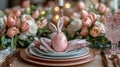 Pink Easter egg with bunny-ear bow on layered plates and napkin. Surrounded by tulips and glassware. Ideal for Easter Royalty Free Stock Photo