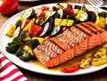 A plate of grilled salmon, vegetables, and fruit on a red and white striped tablecloth. Royalty Free Stock Photo