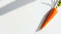 A bright orange carrot with a green stem and leaf sits on a white surface. Royalty Free Stock Photo