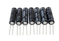 Six black cylindrical capacitors with metal leads displayed in a row Royalty Free Stock Photo