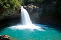 The image shows a small waterfall in a lush green forest with clear water and jagged rocks Royalty Free Stock Photo