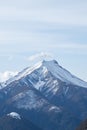 The image shows a snow-covered mountain with trees in the foreground and a sky with clouds in the background. A Royalty Free Stock Photo