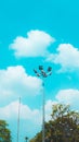 The image shows a street light against a blue sky with clouds in the background. There is also a tree . Royalty Free Stock Photo