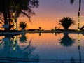 A swimming pool at a resort during a sunset.Â The scene is illuminated by string lights hanging above the pool Royalty Free Stock Photo