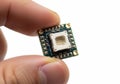 Small electronic module with camera sensor held between fingers for inspection Royalty Free Stock Photo