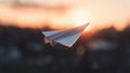 A paper airplane in flight against a sunset. Royalty Free Stock Photo