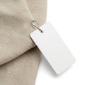 A white rectangular tag attached to a beige fabric with a silver ring Royalty Free Stock Photo