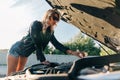 Image on side of blonde standing in front of black car with open hood Royalty Free Stock Photo