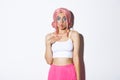 Image of silly pretty girl in pink wig, making surprised face and sucking lips, standing amazed over white background Royalty Free Stock Photo