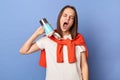 Image of sleepy tired Caucasian woman wearing white T-shirt and orange sweater tied over shoulders standing isolated on blue Royalty Free Stock Photo