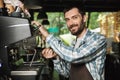 Image of smiling barista man making coffee while working in cafe or coffeehouse outdoor