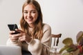 Image of smiling caucasian woman using laptop and smartphone Royalty Free Stock Photo