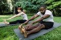 Image of smiling fitness multiethnic couple, wearing sports clothes, working out and stretching legs while sitting on Royalty Free Stock Photo