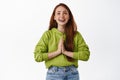 Image of smiling hopeful girl makes wish, holding hands in pray, praying or supplicating, wishing for something, looking