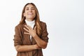 Image of smiling middle aged woman in brown suit, laughing and watching something funny, standing over white background Royalty Free Stock Photo