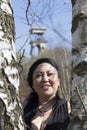 Image of a smiling woman in the middle of two tree trunks with a tower of a mine background Royalty Free Stock Photo