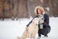 Image of smiling woman squatting next to labrador with toy in teeth in winter park Royalty Free Stock Photo