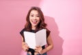 Image of smiling young woman posing isolated over pink background wall holding book reading Royalty Free Stock Photo
