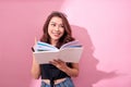 Image of smiling young woman posing  over pink background wall holding book reading Royalty Free Stock Photo