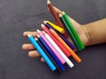 Some colorful wooden pencil hold in a child hand on black background