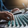 Image Sound engineer adjusting knobs on mixing desk, music production