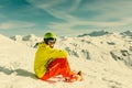 Image of sportive man wearing helmet wearing yellow jacket sitting on snowy slope Royalty Free Stock Photo