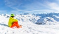 Image of sportive man wearing helmet wearing yellow jacket sitting on snowy slope Royalty Free Stock Photo