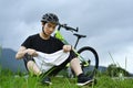 Image of sporty man resting from riding a bicycle, sitting at country road. Travel, sport and active lifestyle concept. Royalty Free Stock Photo