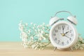 Image of spring Time Change. Summer back concept. Vintage alarm Clock over wooden table.