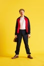 Image of squinting young sport coach dressed in sport wear and holding purse and cap over bright yellow studio