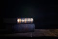 image of stack of antique books over wooden table and dark background.