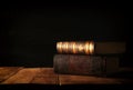 image of stack of antique books over wooden table and dark background.