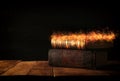 image of stack of antique books over wooden table and dark background.