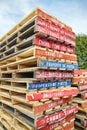 Stack of multicolored red and blue and white pallets in front of a forest in the background on a slightly cloudy day