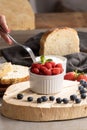 A vertical shot of a fork dipping into a bowl of fresh raspberries in a bowl Royalty Free Stock Photo