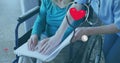 Image of sthetoscope with heart over caucasian nurse and patient reading braille Royalty Free Stock Photo