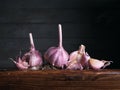 Image of Still Life with stack of Garlic. Dark wood background, antique wooden table