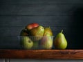 Image of Still Life with stack of green Pears. Dark wood background, antique wooden table