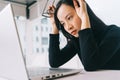Image of stressed asian woman working from home on laptop looking worried, tired and overwhelmed