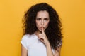 Image of strict woman 20s with curly hair holding finger at lips Royalty Free Stock Photo