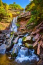 Stunning terraced waterfalls small and large from below over mossy rocks surrounded by New York fall foliage Royalty Free Stock Photo