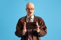 Image of surprised balded and mustache young man in glasses with box in hands over blue studio background.