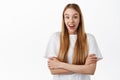 Image of surprised blond girl, gasping amazed, raising eyebrows excited and impressed, cross arms on chest, standing in Royalty Free Stock Photo