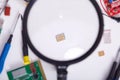 Image of table with small electronic parts of pc or smart phone, computer ram through magnifying glass, desktop with broken Royalty Free Stock Photo